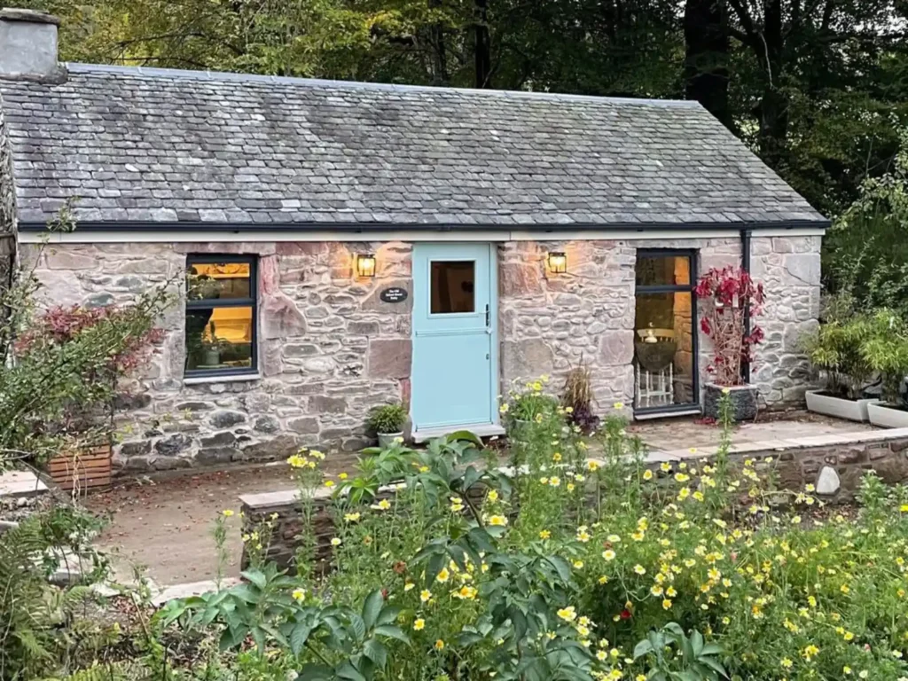 Exterior of the Old School House Bothy surrounded by plants.