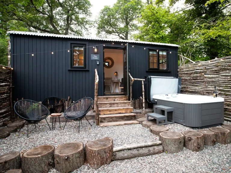 Exterior of the Mar Huts in Loch Lomond showing cabin with hot tub and outdoor seating area.