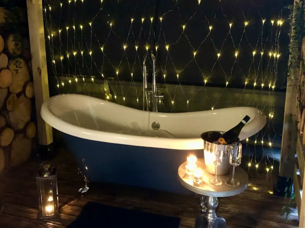 Outdoor tub with champagne and glasses on the table at the Loch Lomond Hideaways.