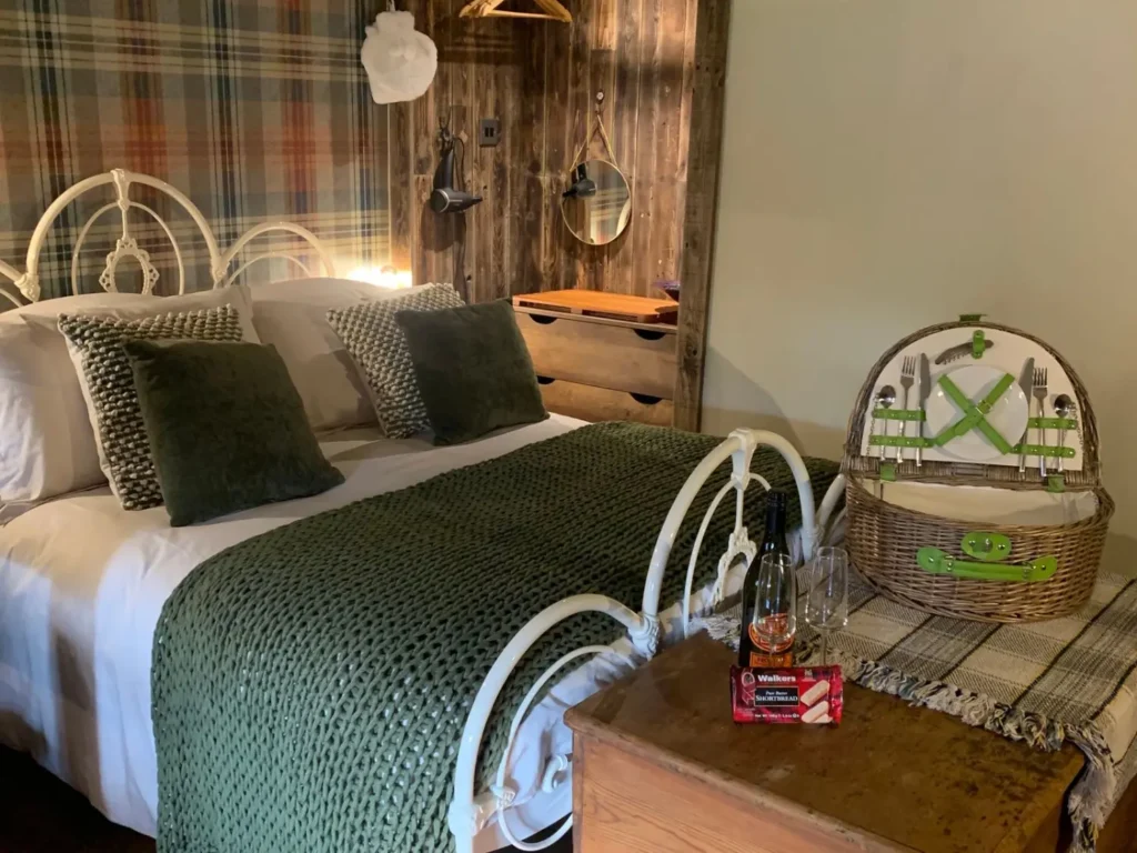 Interior of the Watermill Nook cabin in Loch Lomond show bed and table at the end of the bed with picnic basket on top.