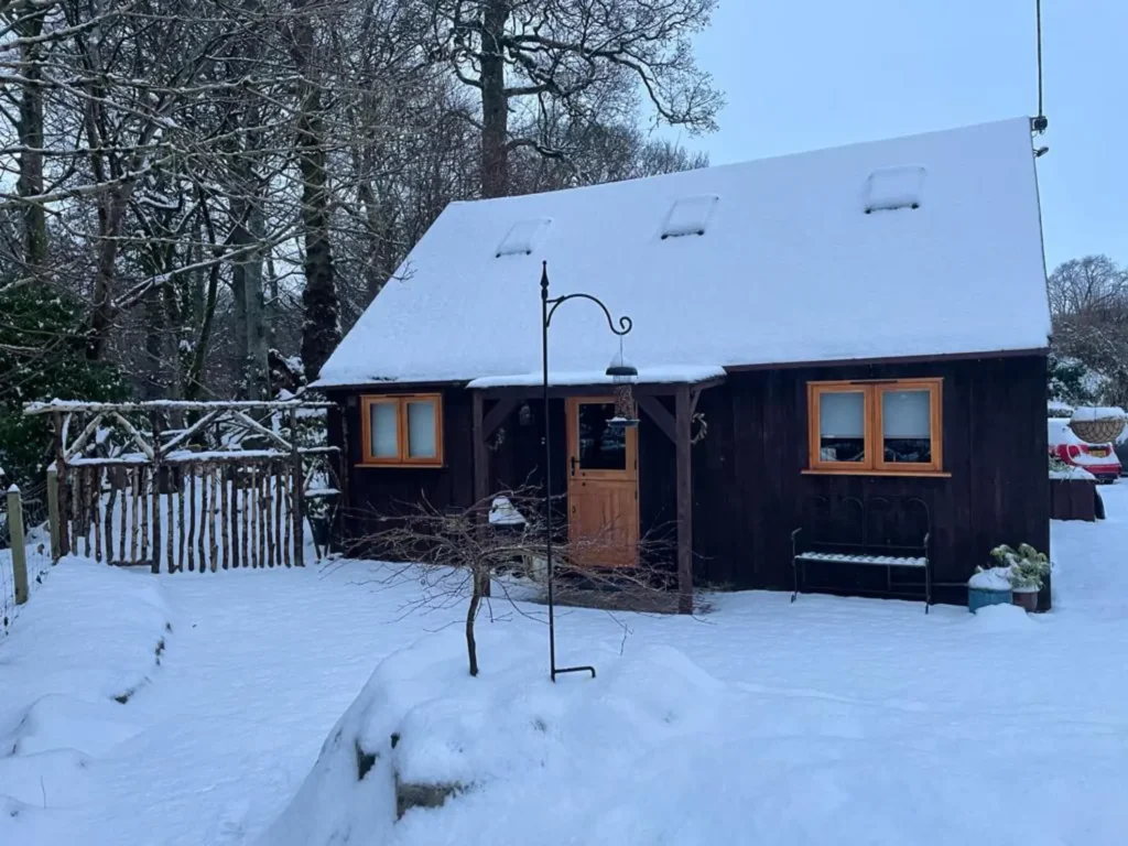 Exterior of the Watermill Nook cabin in Loch Lomond in Winter covered in snow.