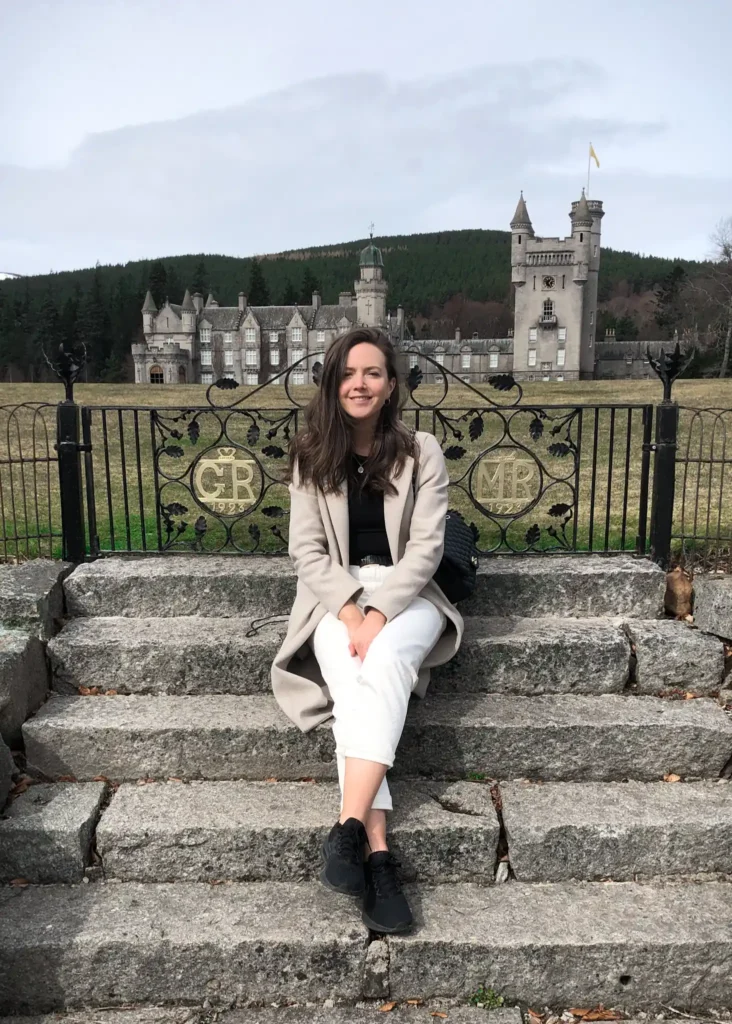 Girl sitting down on steps with Balmoral Castle in the background.