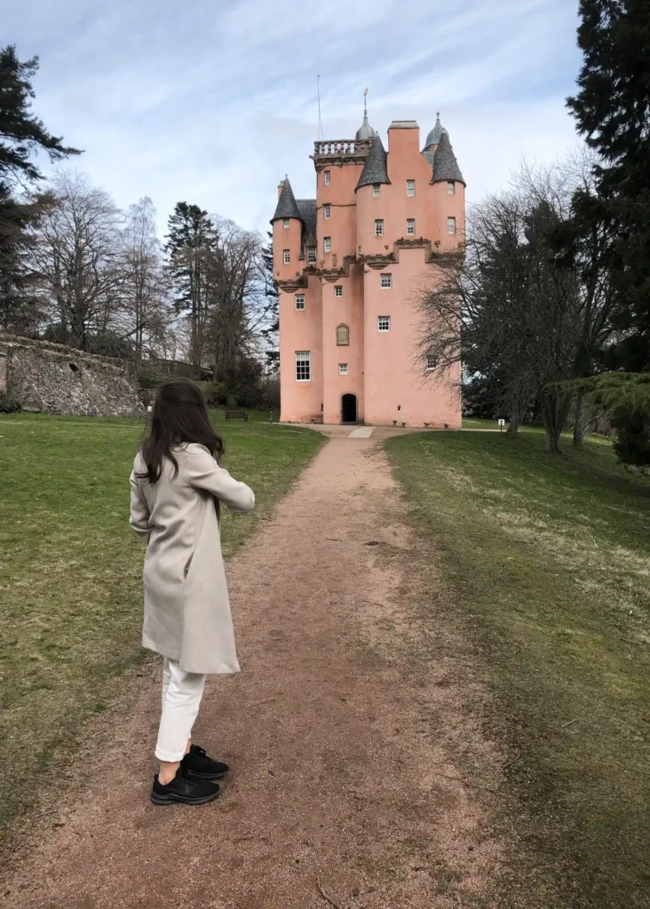 Girl standing side on to the camera looking at Craigievar Castle in the background.