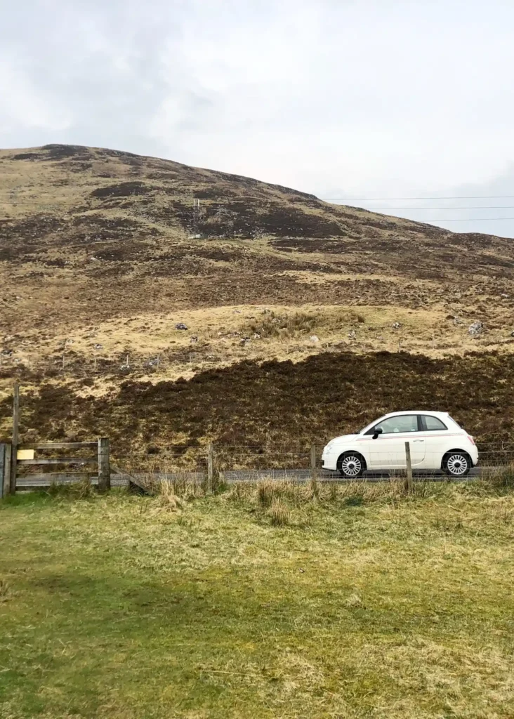 Side on picture of a Fiat 500 with hills in the background on the NE250 in Scotland.