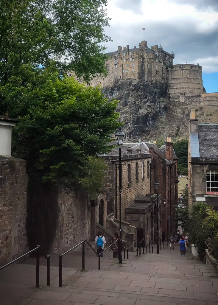 Stairs down to the Grassmarket in Edinburgh with houses either side and Edinburgh Castle in the background. 