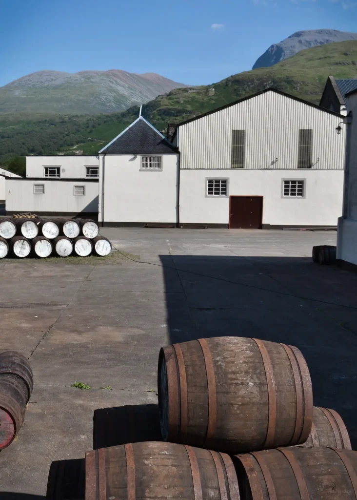 Barrels outside Ben Nevis Distillery with the Nevis mountain range in the background on a sunny day.