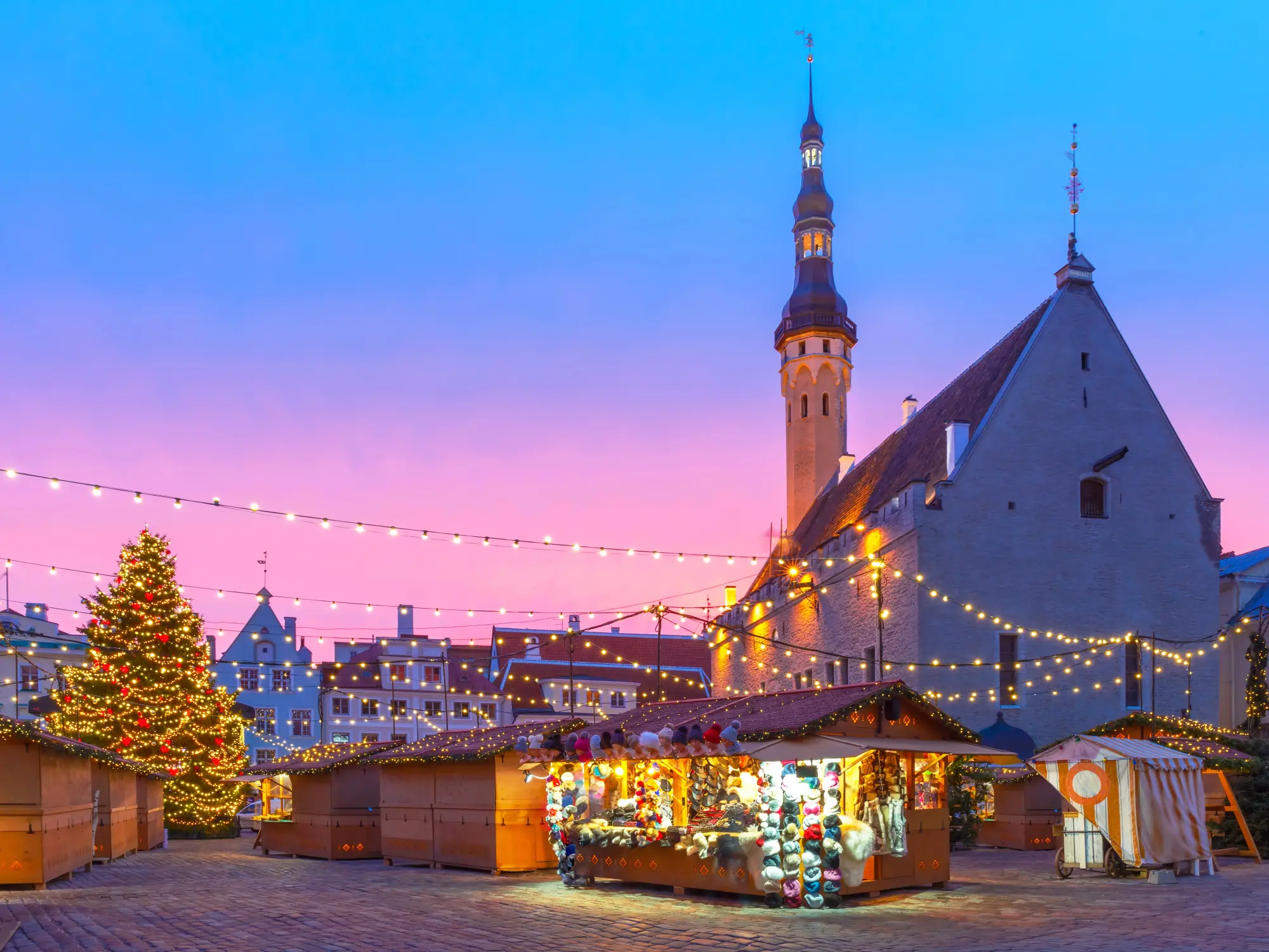 Decorated and illuminated Christmas tree and Christmas Market at the Town Hall square in Tallinn at sunrise.