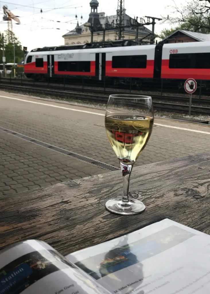 Sitting outside at a table with menu open and a glass of wine with a OBB train going past at a station in Austria.