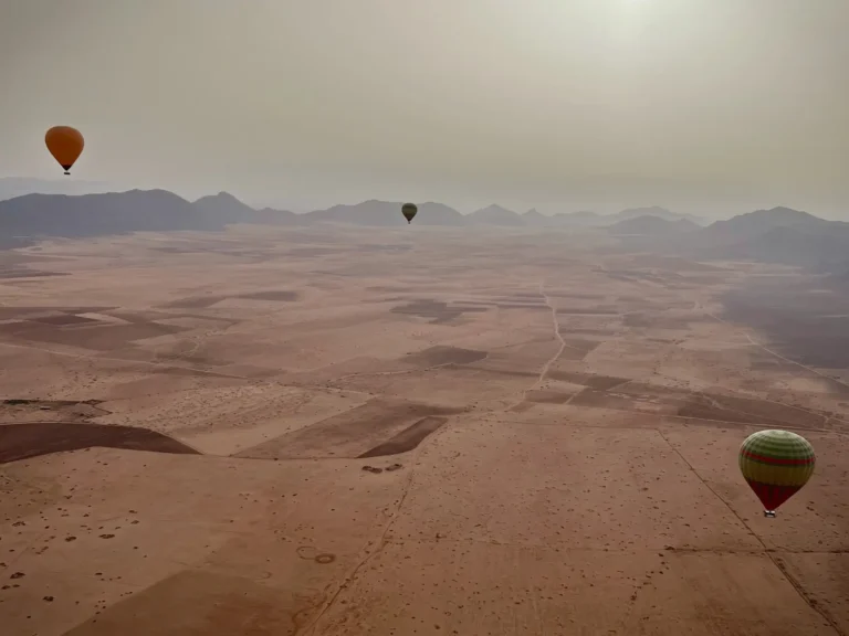 Hot air balloon ride in Morocco at sunrise. With mountains and other balloons in distance.