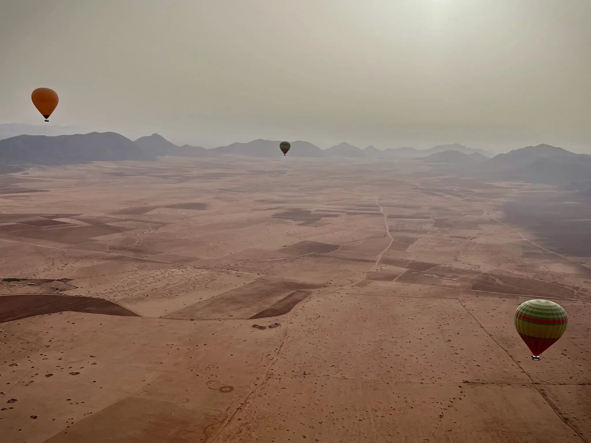 Hot air balloon ride in Morocco at sunrise. With mountains and other balloons in distance.