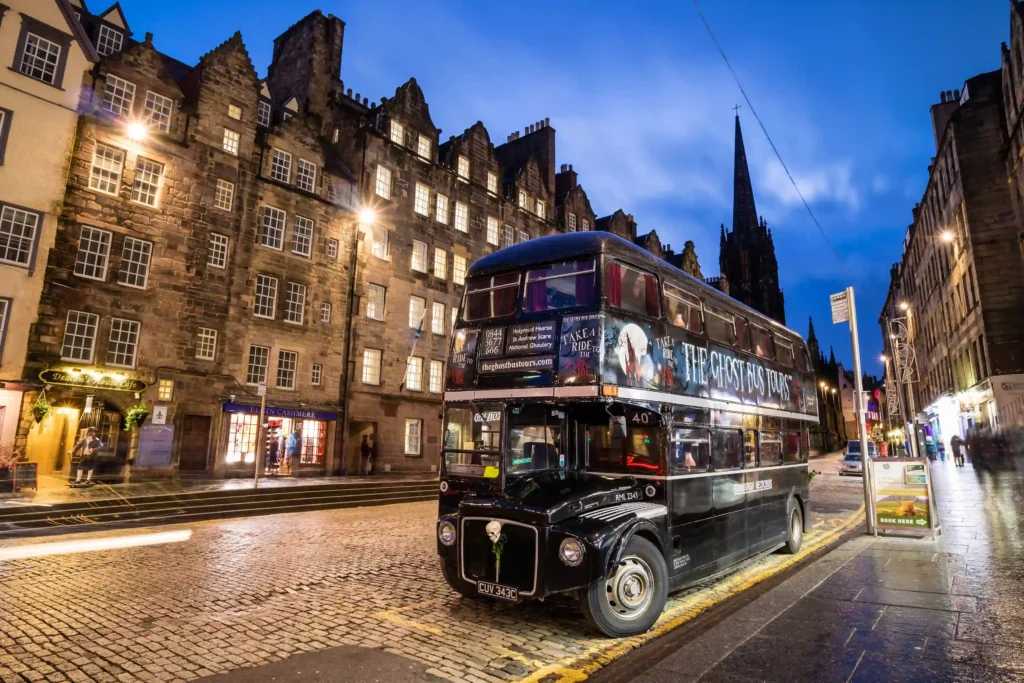 Street view of the historic Royal Mile with the ghost bus tour parked next to a bus station.