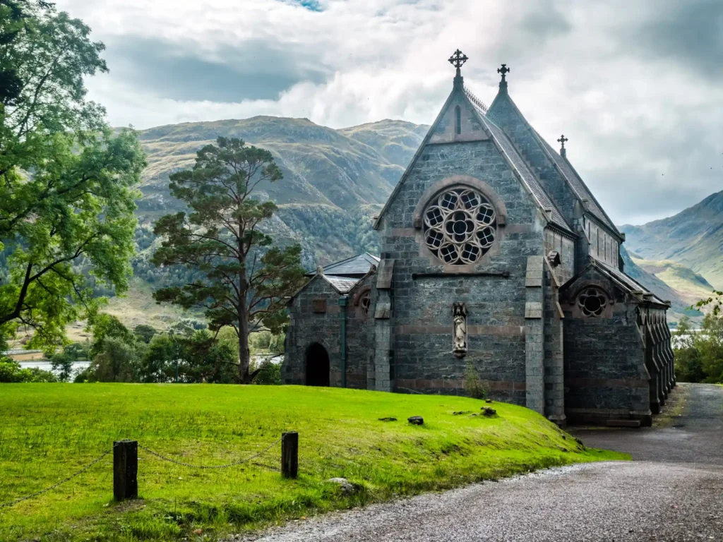 View of Glenfinnan Church with hills surrounding Loch Shiel in the background.