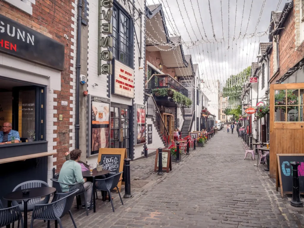Ashton Lane in Glasgow during the day with a couple sitting outside drinking.