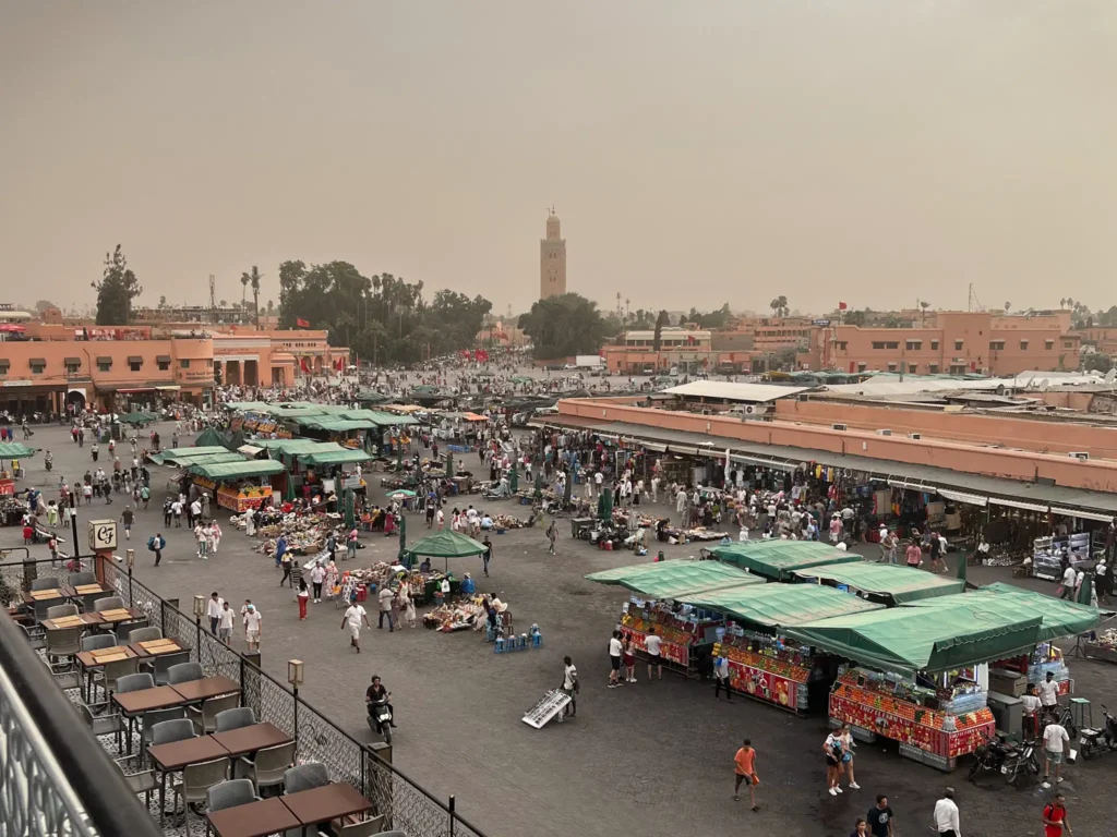 Jemaa el-Fnaa in Marrakech at sunset as people are setting up stalls and crowds are starting to gather.
