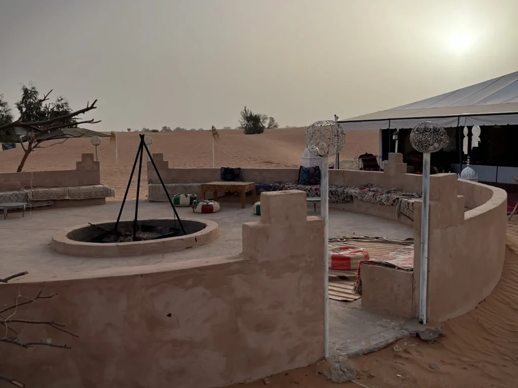 Seating area at desert camp in Merzouga with camp fire and hazy desert sky.
