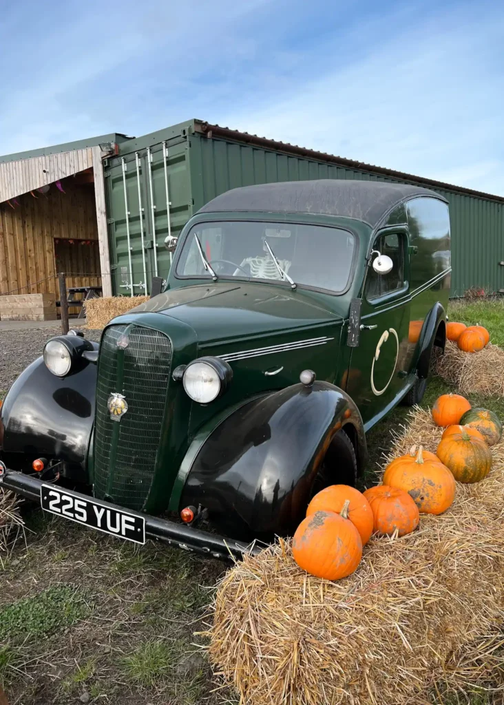 Old car with skeleton as the driver surrounded by hay bales and pumpkins at Craigie's Farm.