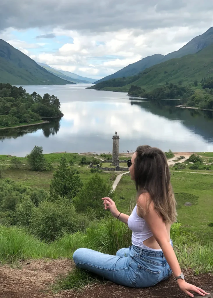 Girl sitting with back to camera looking over Loch Shiel in the Scottish Highlands.
