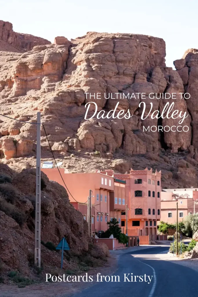 Pinterest Pin showing road going through the Dades Valley in Morocco leading up to houses. There's text over the top reading "The ultimate guide to Dades Valley Morocco" and "Postcards from Kirsty"