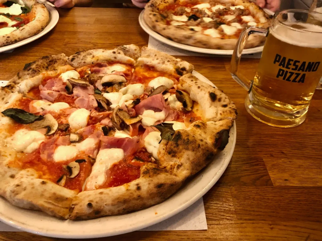 Woodfired pizza with mushrooms and ham, and a beer from paesano pizza in Glasgow city centre.