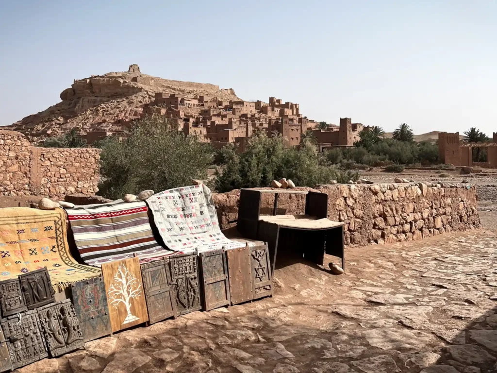 The tourist shops selling rugs and wooden decorations with Ait Ben Haddou in the background.