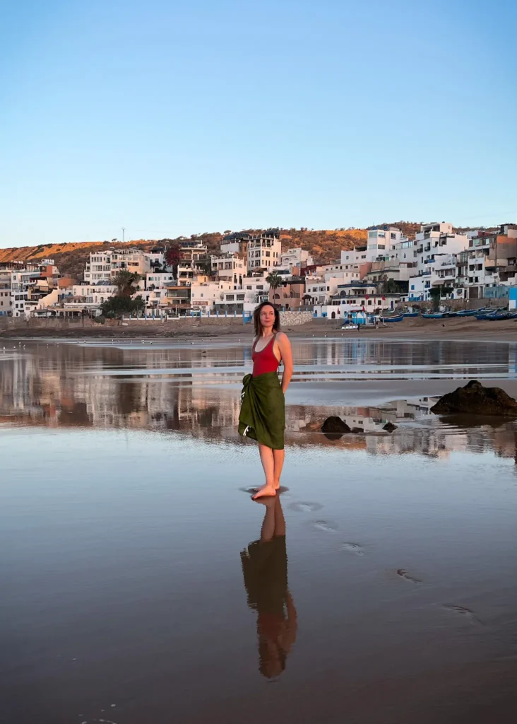 Girl standing on Taghazout beach at sunrise looking off into the distance.