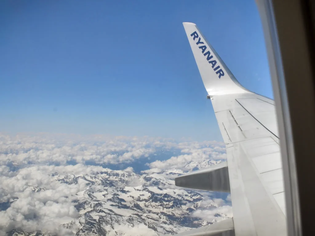 Ryanair flight to London Stansted airport. View of the wing with the Ryanair logo with the background of the mountain landscape. 