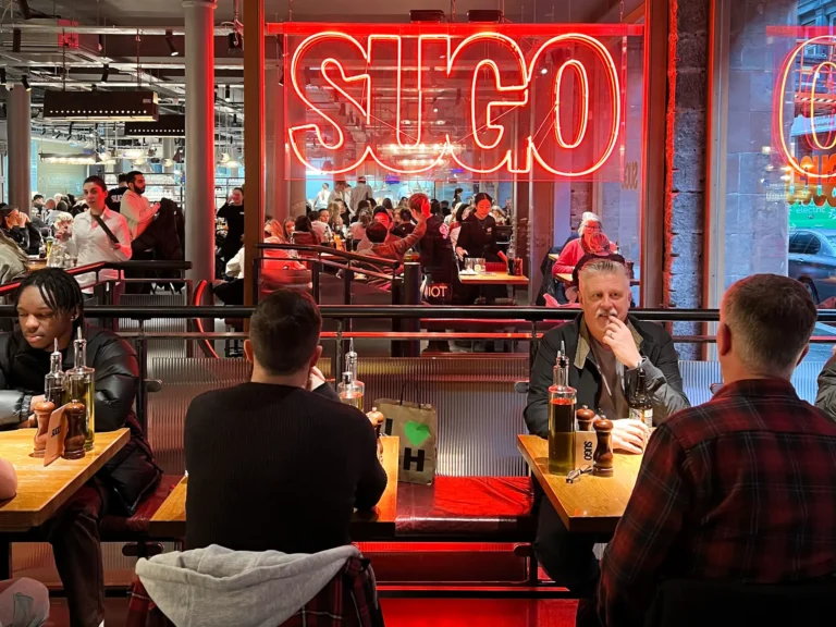 Inside sugo restaurant with people dining and sign.
