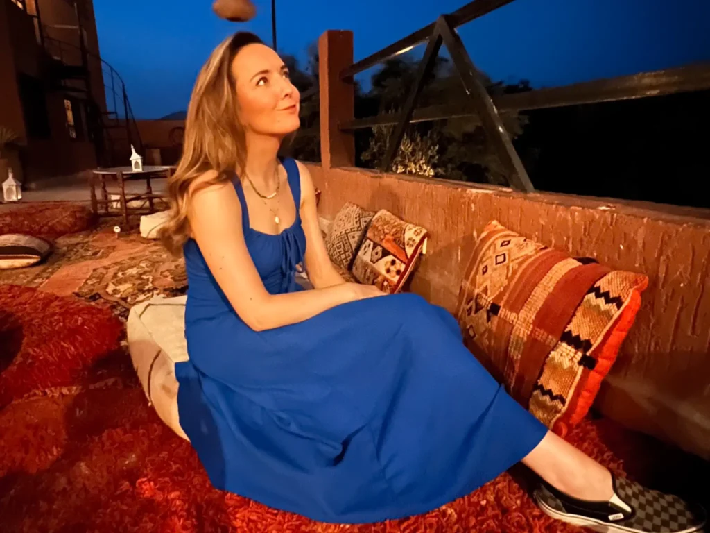 Girl in a blue dress stargazing on a Moroccan terrace in Dades Valley.