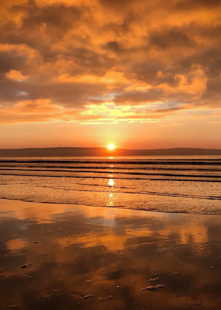 Sunset on Dunnet Bay with water reflecting the sky and clouds above.