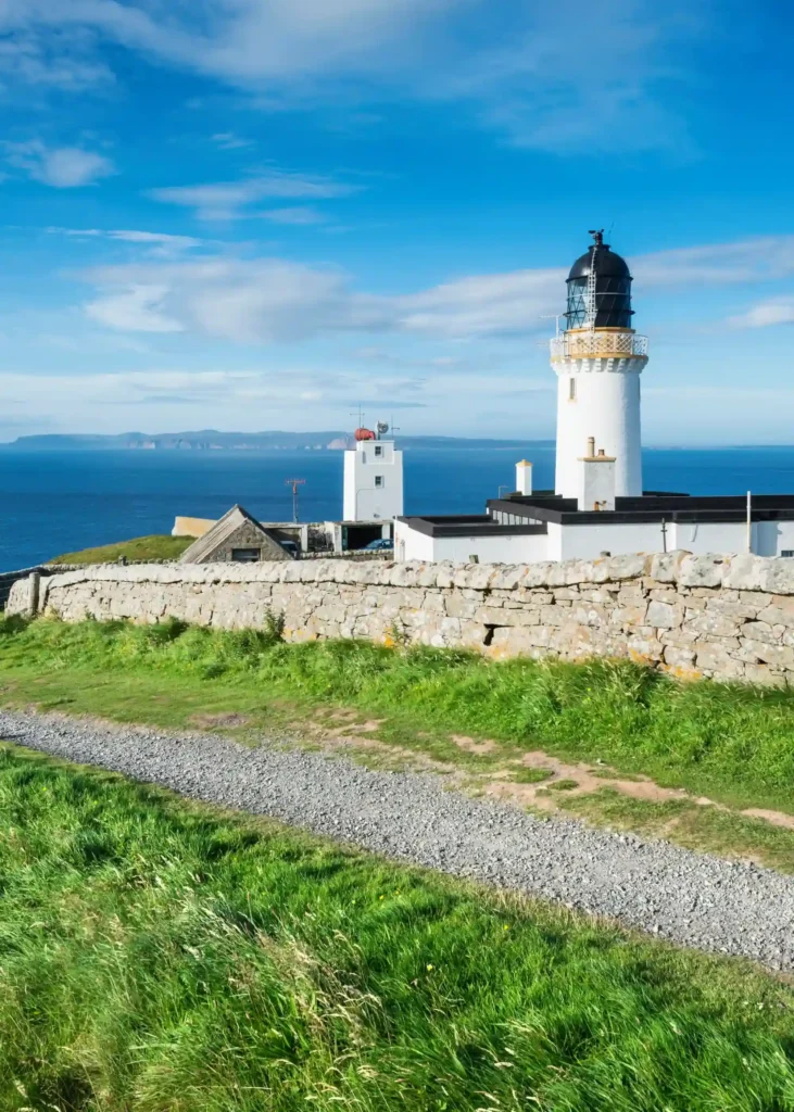Dunnet head lighthouse on the north coast of scotland, orkney islands at back on the horizon.