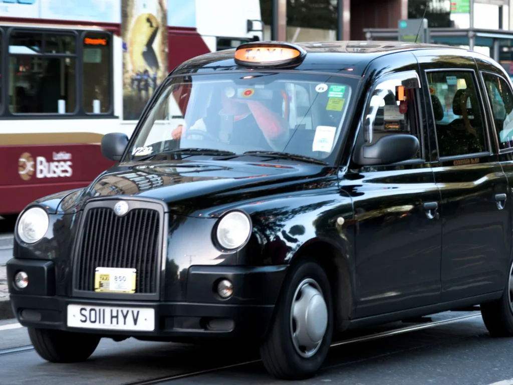 Black taxi on Princes Street in Edinburgh, scotland, with light on.