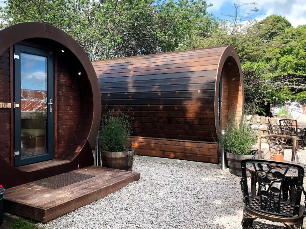 Delny glamping pods with outdoor dining tables on a sunny day.