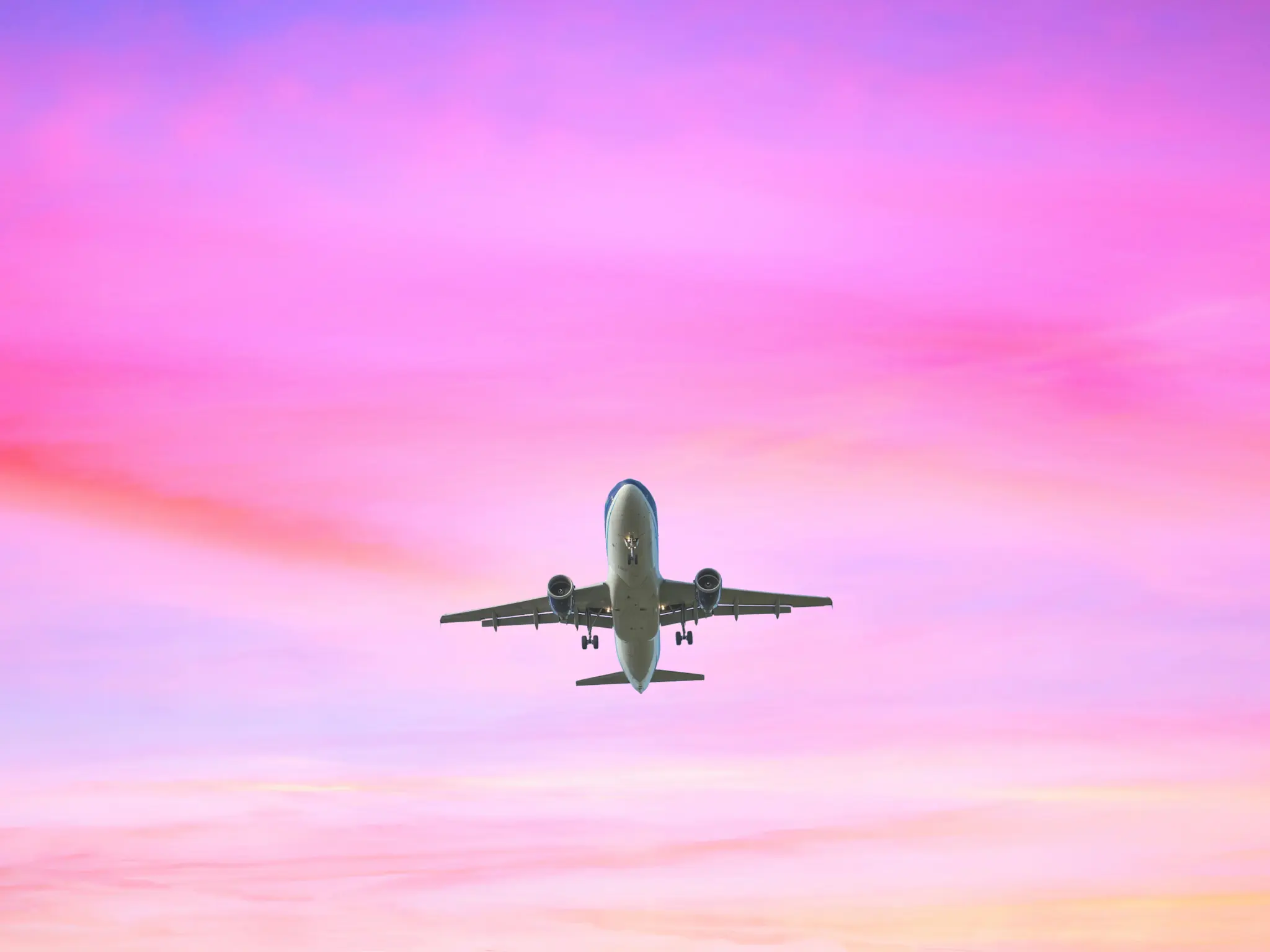Landing airplane on the pastel colored sky background.