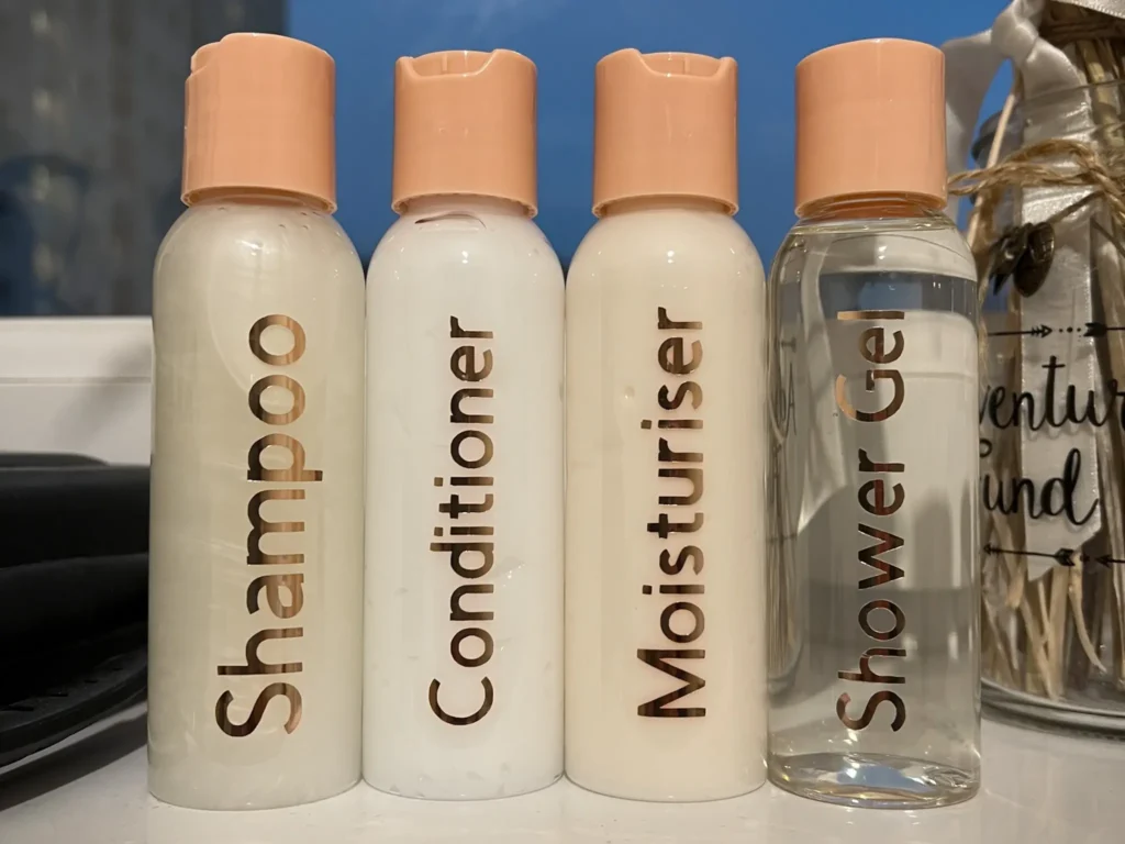 Four travel bottles labelled shampoo, condition, moisturiser and shower gel.