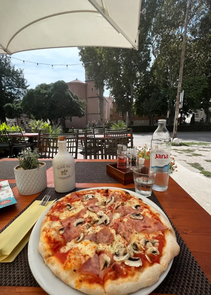 Pizza with mushrooms and ham at a quiet restaurant in Zadar, Croatia.