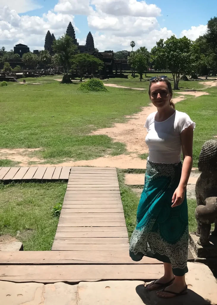 Girl standing smiling at the camera with Angkor Wat in Cambodia in the background.