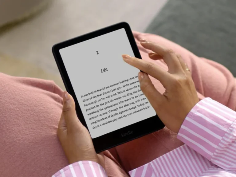Women with striped shirt and pink trousers holding a black Kindle paperwhite