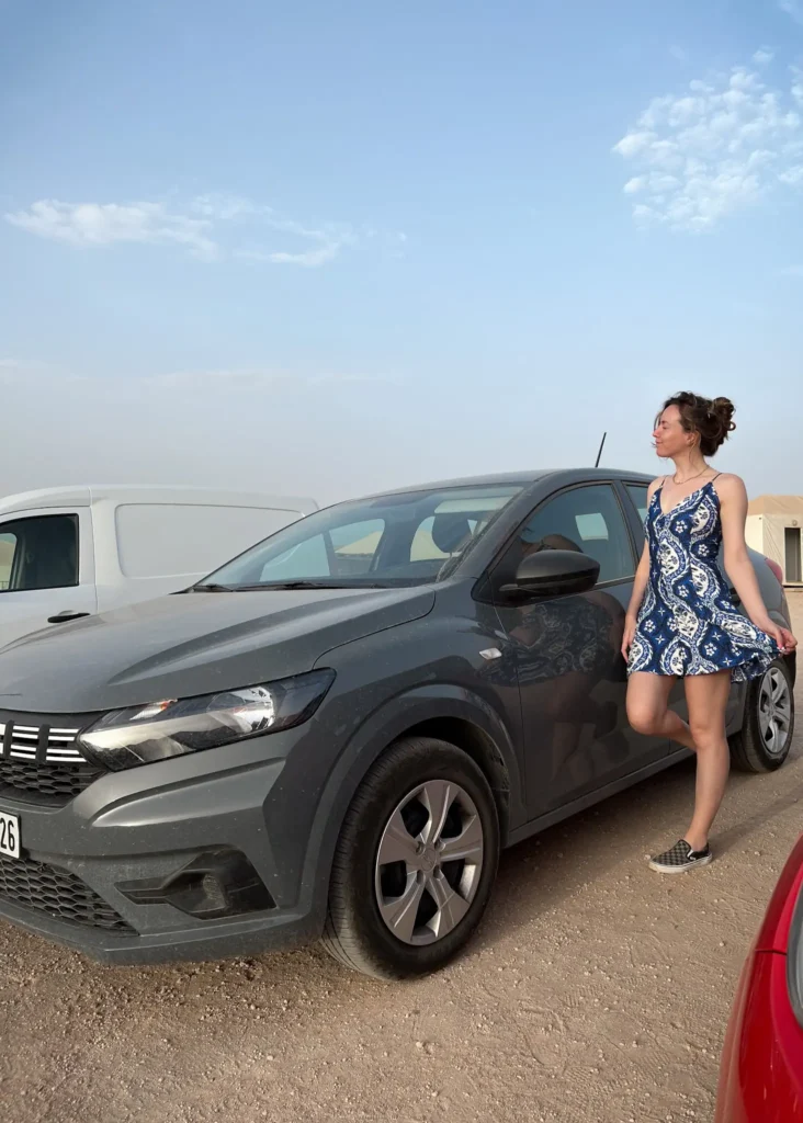 Girl standing in front of her rental car in Agafay Desert Morocco.