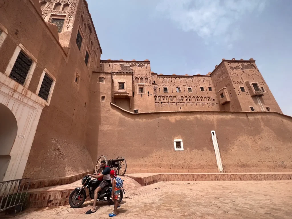 Man on motorcycle with son in front of Kasbah Taourirt in Ouarzazate.