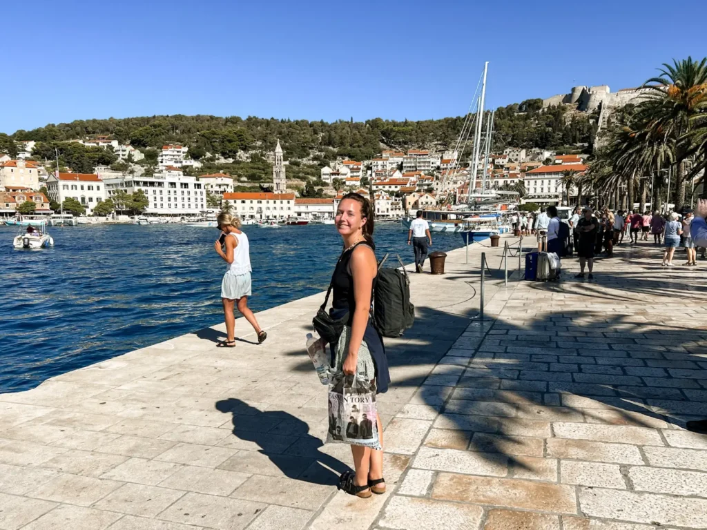 Girl standing smiling at the camera on Hvar Old Town promenade.