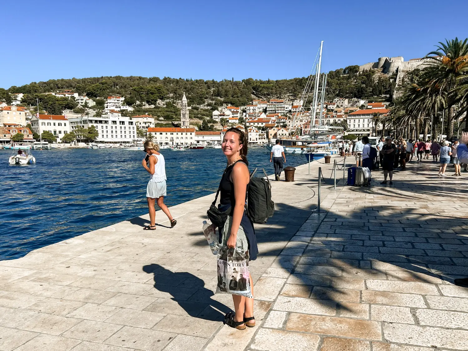 Girl standing smiling at the camera on Hvar Old Town promenade.