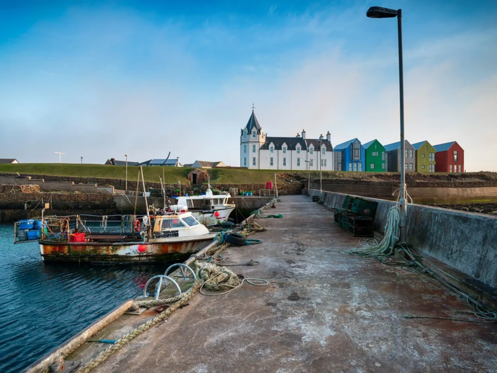 Looking over boats and John o'Groats from the harbour on a sunny day.