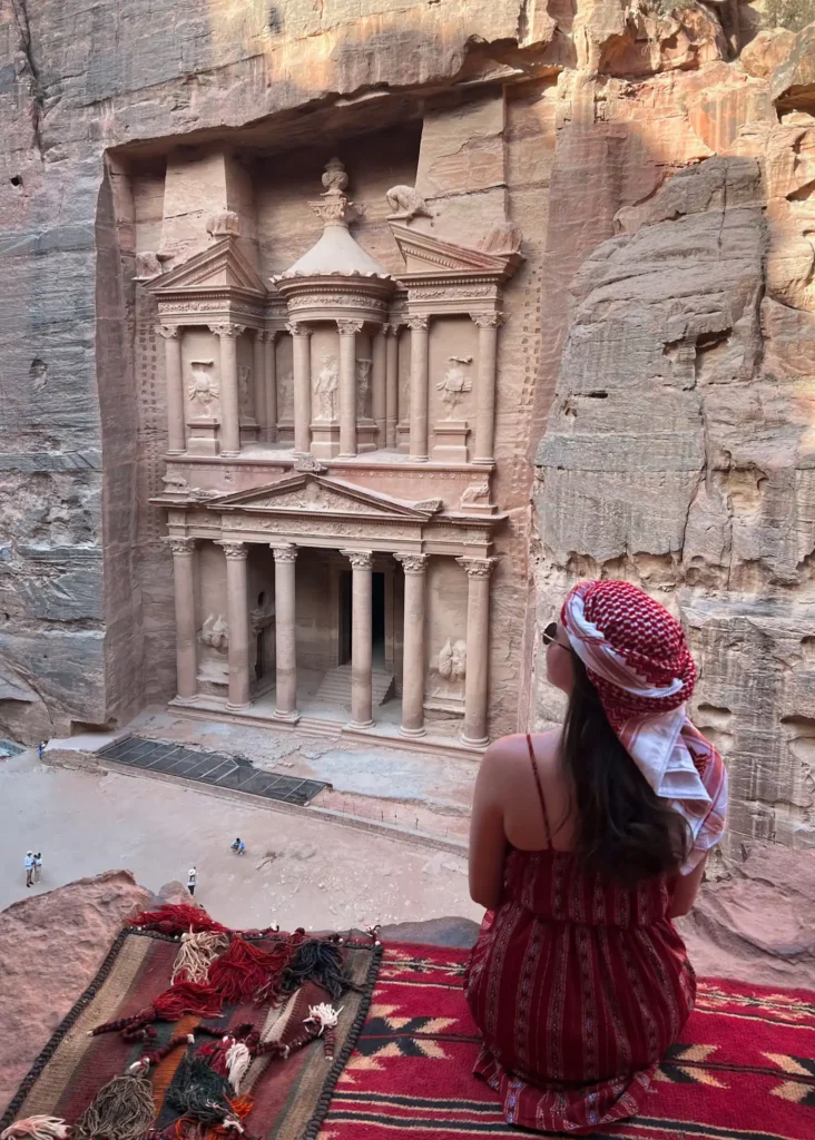 Girl sitting with back to the camera looking at Petra in Jordan.