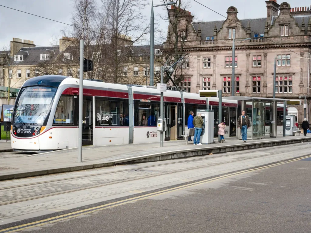 People getting on and off the tram in St Andrew Square in Edinburgh city centre on a cloudy -winter day.
