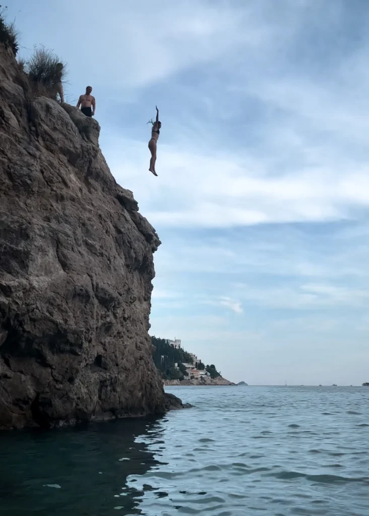 Girl jumping off a climp into the water in Dubrovnik, Croatia