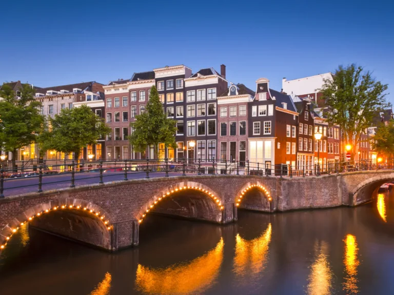 Amsterdam tranquil canals illuminated at night with townhouses in the background.