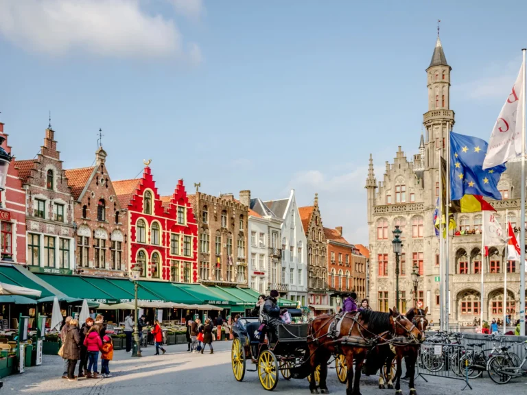 Horse carriages wait for customers on Grote square in Bruges. The Belgian city of Bruges is a famous tourist destination and UNESCO world heritage listed for its medieval center.