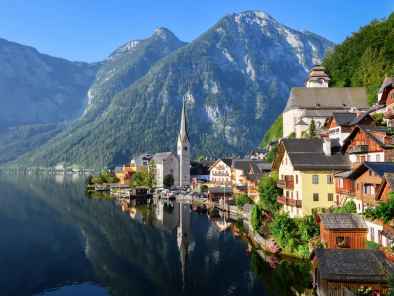 Hallstatt village with church with reflection in the still water of the lake with alps mountains in the background in austria.