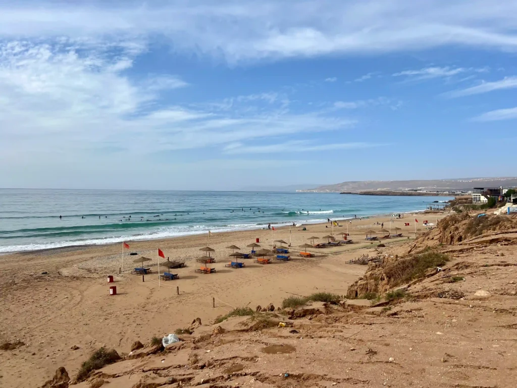 Banana beach in Aourir, Morocco with blue skies and sun loungers and parasols on the beach.