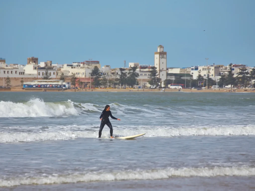 A young female surfer gracefully rides the waves on her board along the shores of essaouira, morocco.